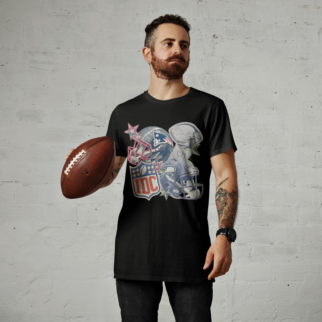 Man wearing a black t-shirt with a graphic design, holding a football against a gray brick wall.